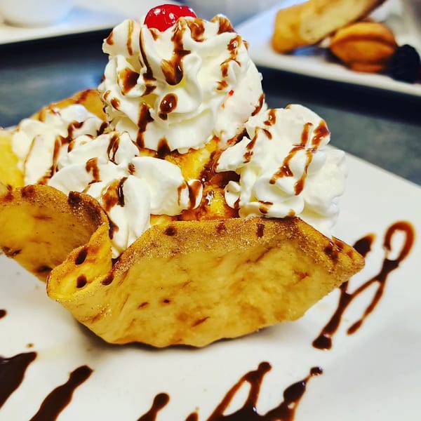 Mucho Bueno's fried ice cream dessert in a crispy shell, topped with whipped cream, chocolate, and a cherry.